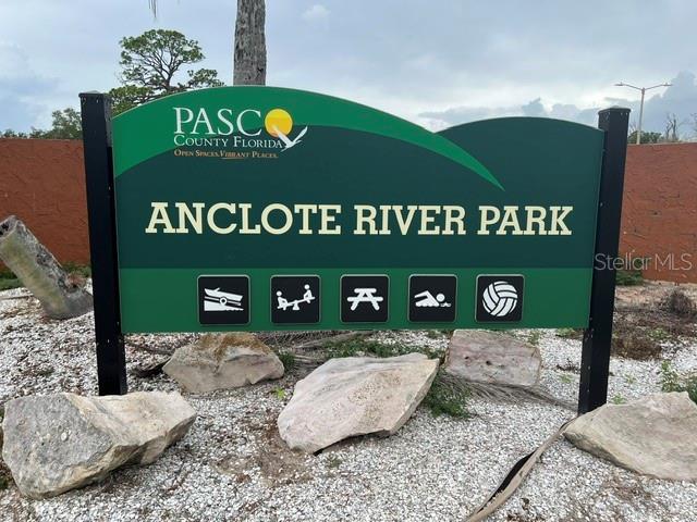 A green sign for Anclote River Park stands in a gravel area with large rocks — 1045 HICKORY LANE, HOLIDAY, FL