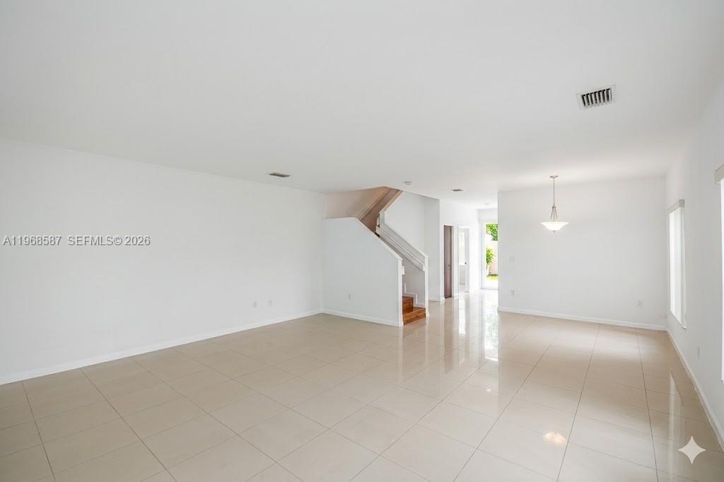 A bright, open-concept living and dining area features white walls and light-colored tile flooring — 2780 SW 33 AVE, Miami FL 33133, MIAMI, FL