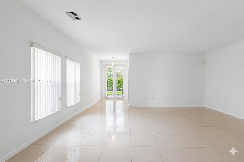An empty room with white walls, tile flooring, vertical blinds, and glass patio doors — 2780 SW 33 AVE, Miami FL 33133, MIAMI, FL