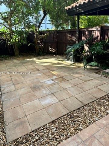 A paved patio area sits in a backyard enclosed by a wooden fence and trees — 9001 SW 94 ST # 113, Miami FL 33176, MIAMI, FL
