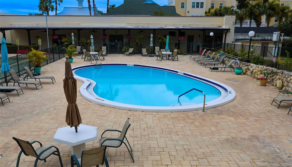 A kidney-shaped swimming pool sits on a paved patio surrounded by lounge chairs and tables — 1235 S HIGHLAND AVENUE UNIT 4-306, CLEARWATER, FL