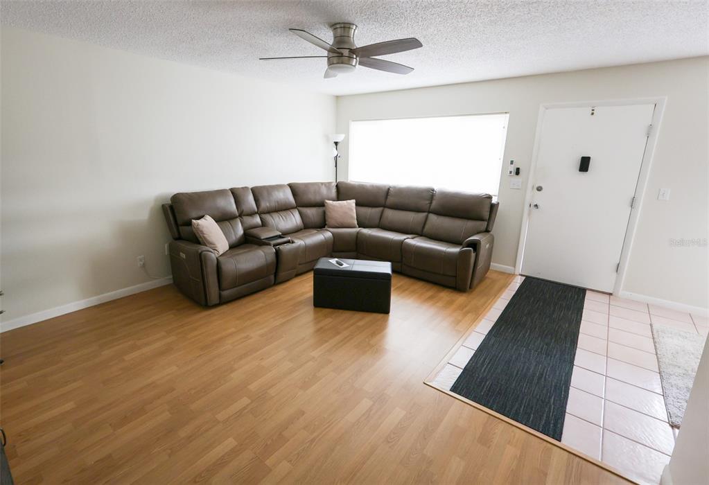 A living room features a brown sectional sofa, wood-look flooring, and a ceiling fan — 1235 S HIGHLAND AVENUE UNIT 4-306, CLEARWATER, FL