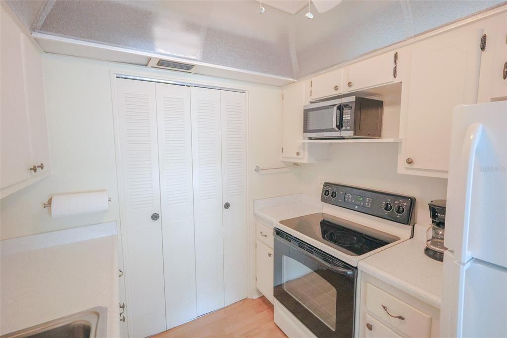 A kitchen features white cabinets, a black electric range, a microwave, and white appliances — 1235 S HIGHLAND AVENUE UNIT 4-306, CLEARWATER, FL
