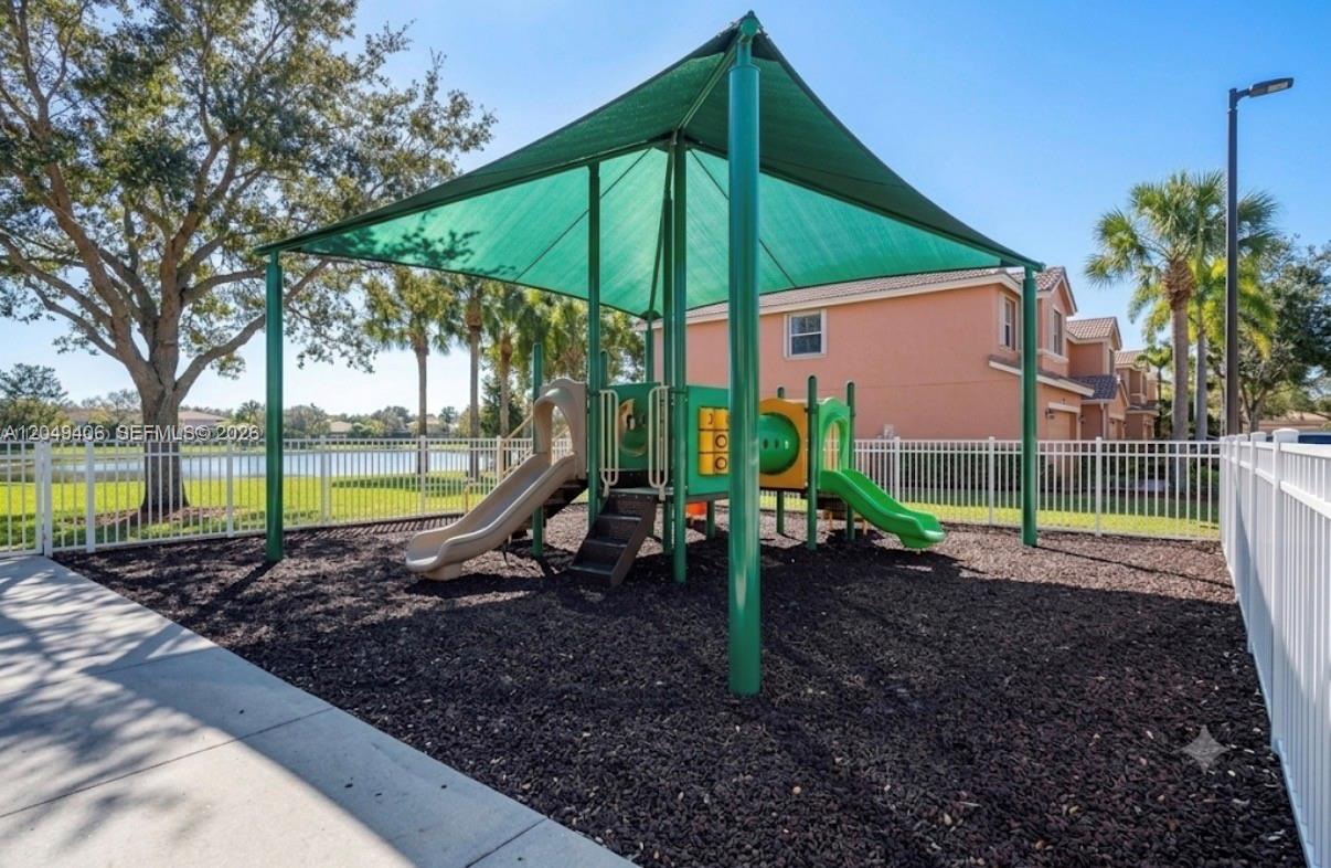 A playground with a green shade canopy, slides, and mulch flooring sits outdoors — 4070 NW 92nd Ave, Sunrise FL 33351, SUNRISE, FL
