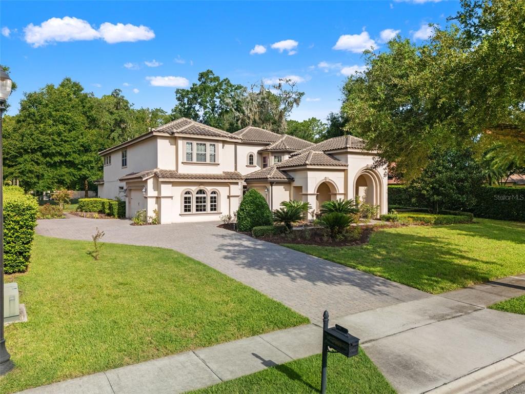 A two-story stucco house with a tiled roof and a paved driveway sits on a lawn — 7361 BELLA FORESTA PLACE, SANFORD, FL