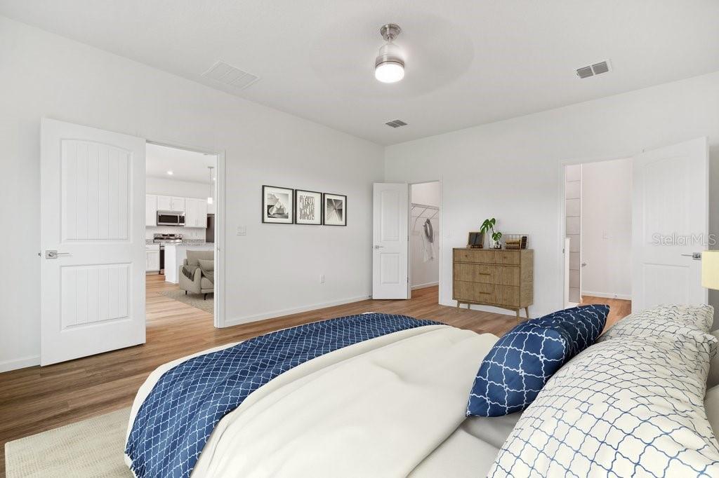 A bedroom with white walls, wood-look flooring, and a view into an adjacent kitchen — 7 BUFFALO BILL DRIVE, PALM COAST, FL