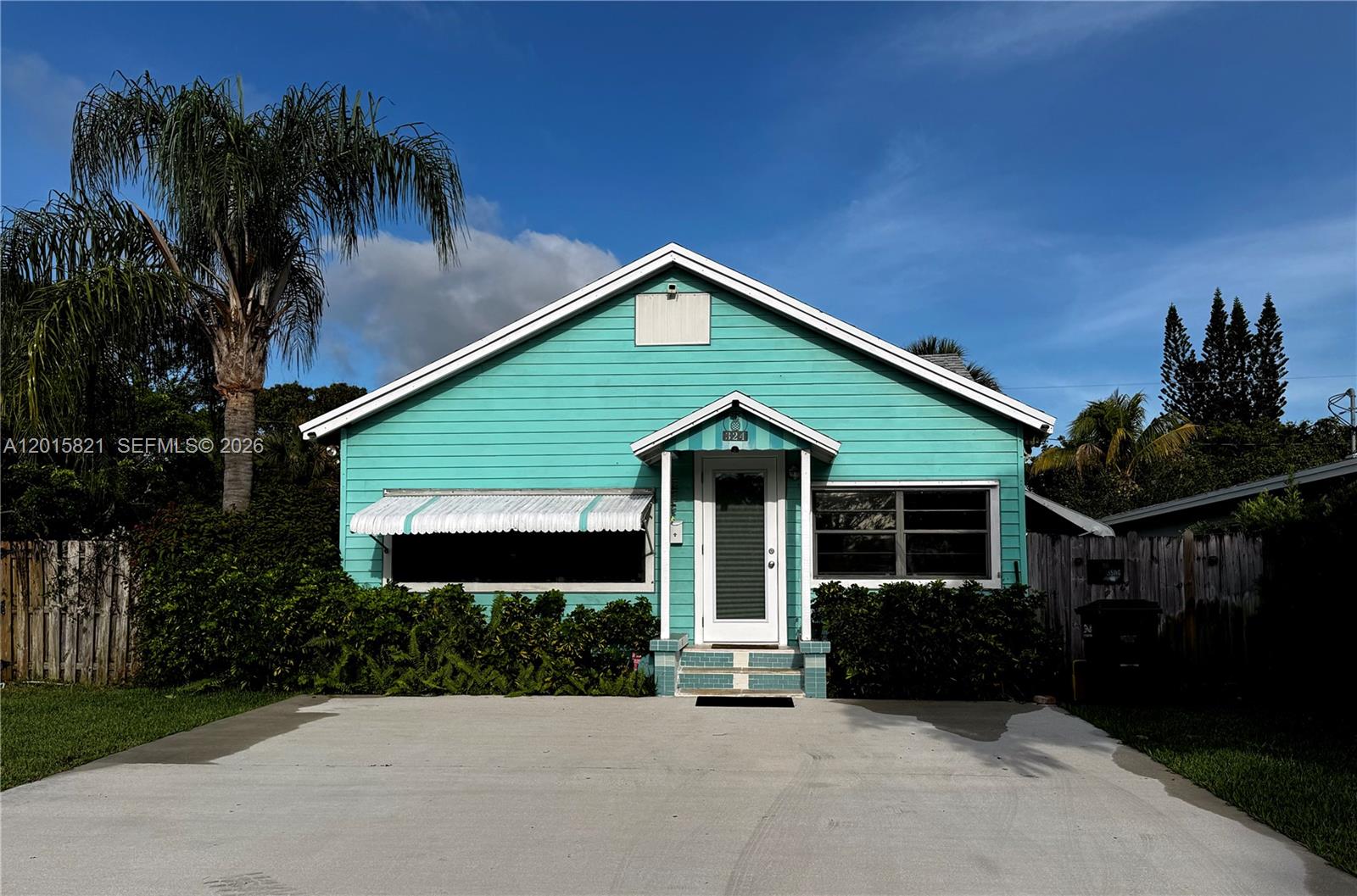 A teal, single-story house with a front porch and concrete driveway sits under a blue sky — 324 SW 3rd Ave, Delray Beach FL 33444, DELRAY BEACH, FL