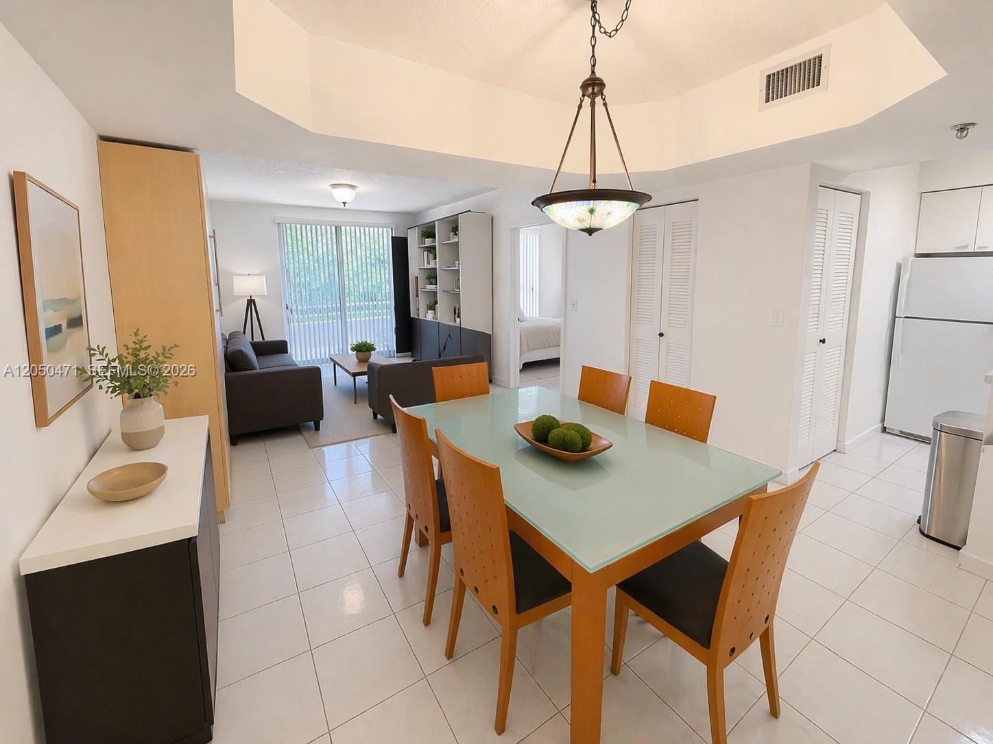 A dining area with a glass-topped table sits adjacent to a living room and kitchen — 9156 Collins Ave # 107, Surfside FL 33154, SURFSIDE, FL