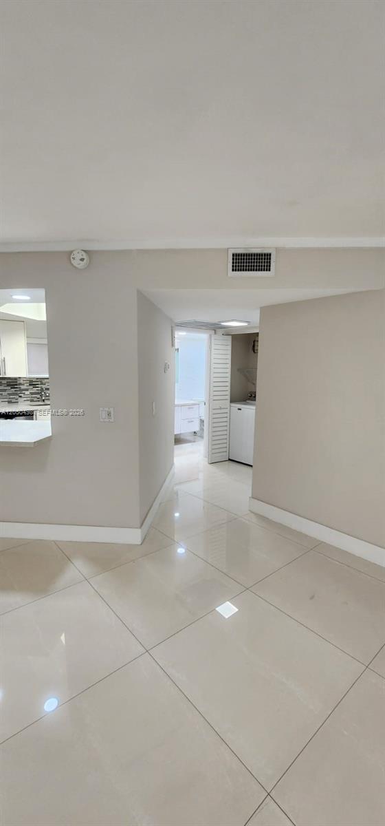 A tiled hallway leads to a laundry closet and a bathroom with white cabinets — 8205 Lake Dr # 101, Doral FL 33166, DORAL, FL