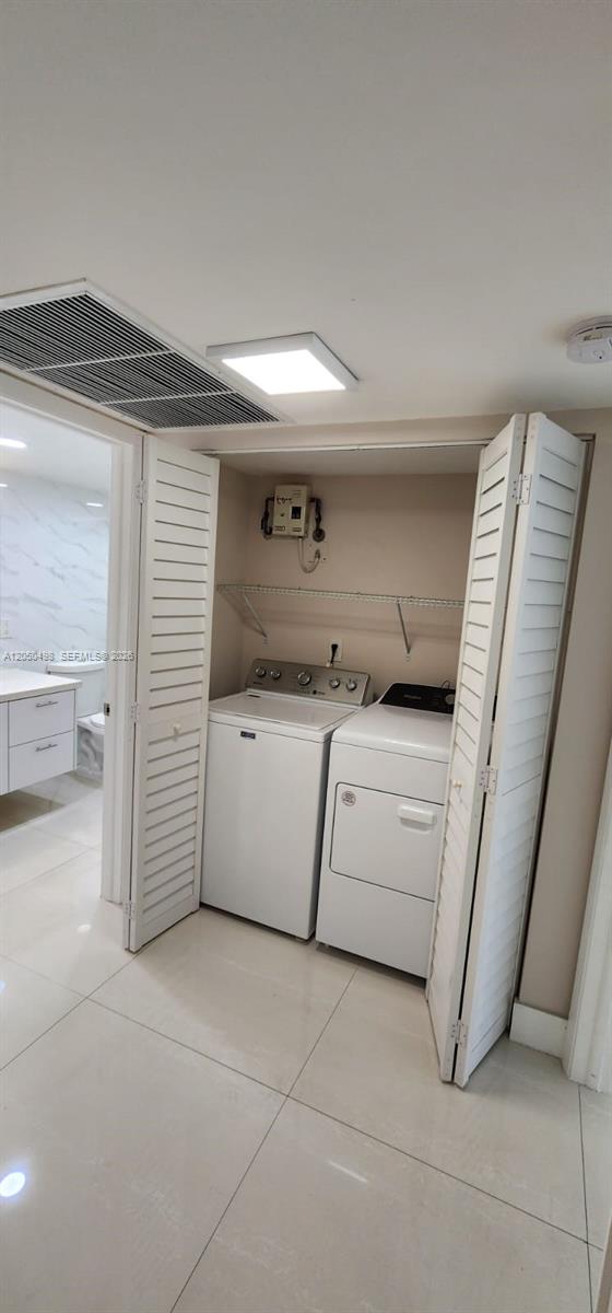 A laundry closet with a washer and dryer sits next to a tiled bathroom — 8205 Lake Dr # 101, Doral FL 33166, DORAL, FL