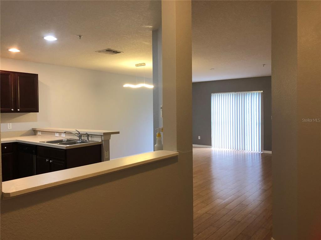 A kitchen with dark cabinets and a breakfast bar overlooks an adjacent living area — 13442 APPLEROSE LANE UNIT 66, ORLANDO, FL