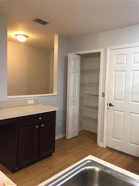 A kitchen features dark wood cabinets, a pantry with wire shelving, and a pass-through window — 13442 APPLEROSE LANE UNIT 66, ORLANDO, FL