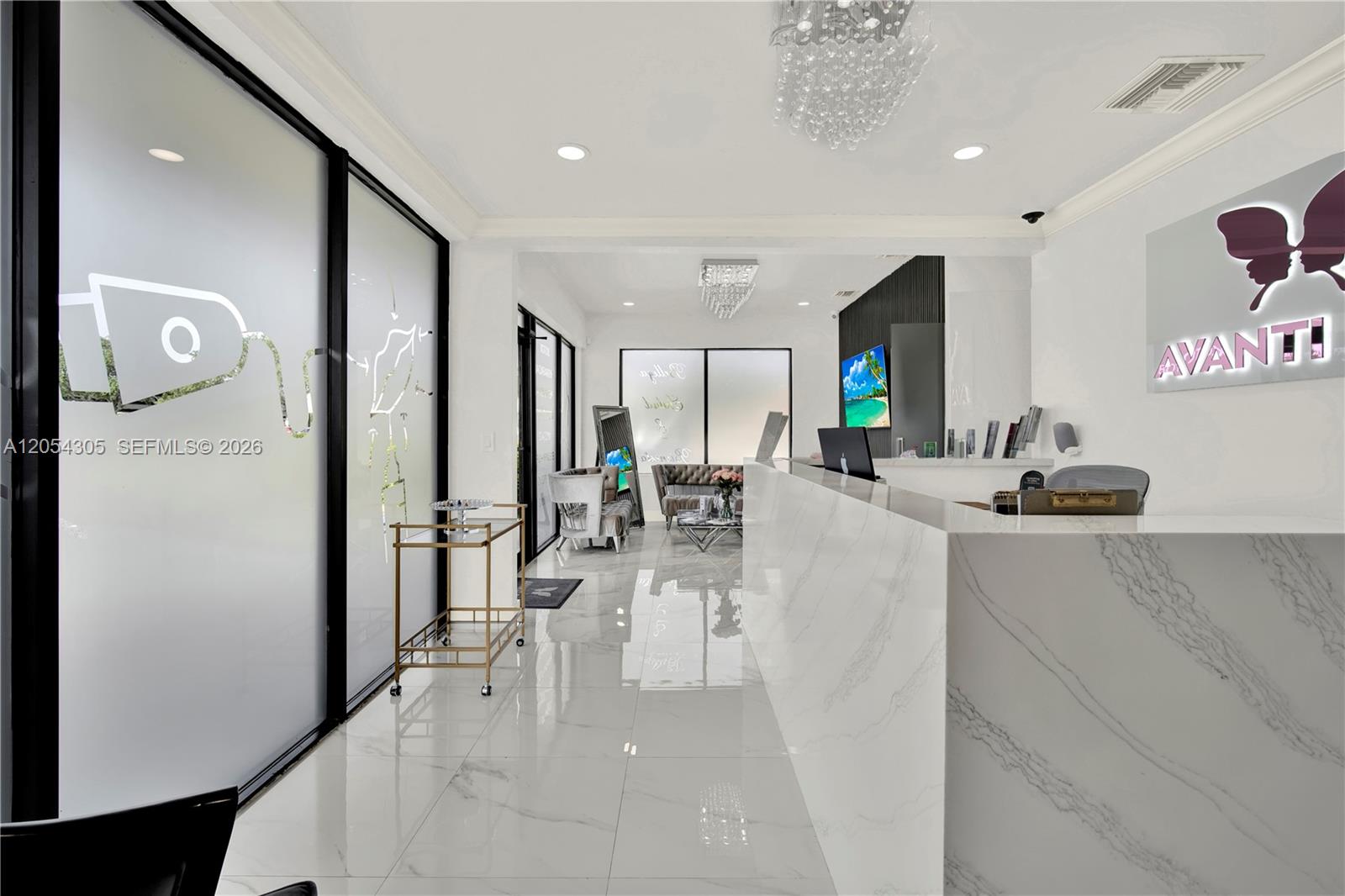 A modern reception area features a marble desk, white tile floors, and a crystal chandelier — 3855 SW 137th Ave, Miami FL 33175, MIAMI, FL