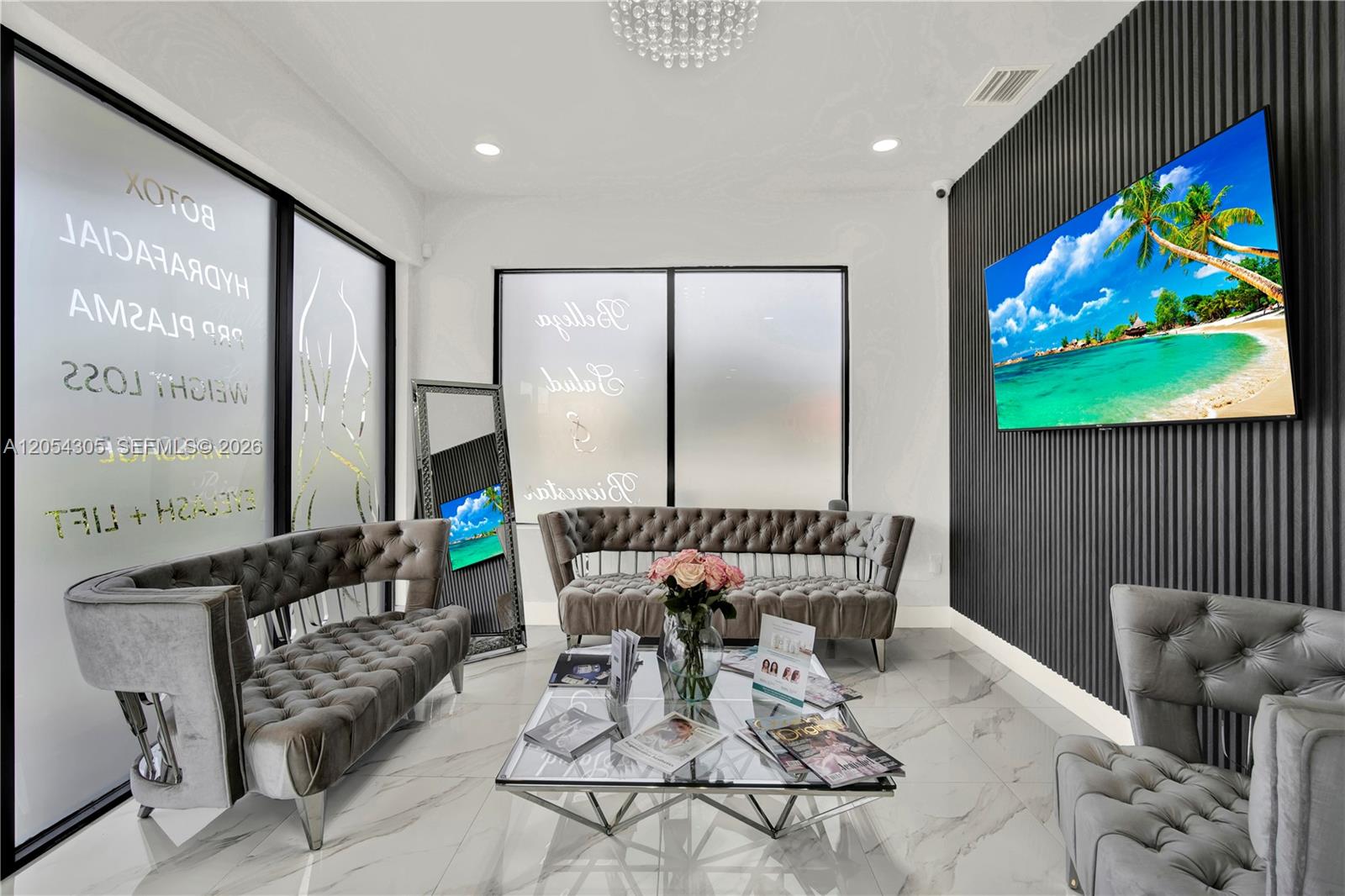 A modern waiting room features tufted grey velvet sofas, a glass coffee table, and a television — 3855 SW 137th Ave, Miami FL 33175, MIAMI, FL