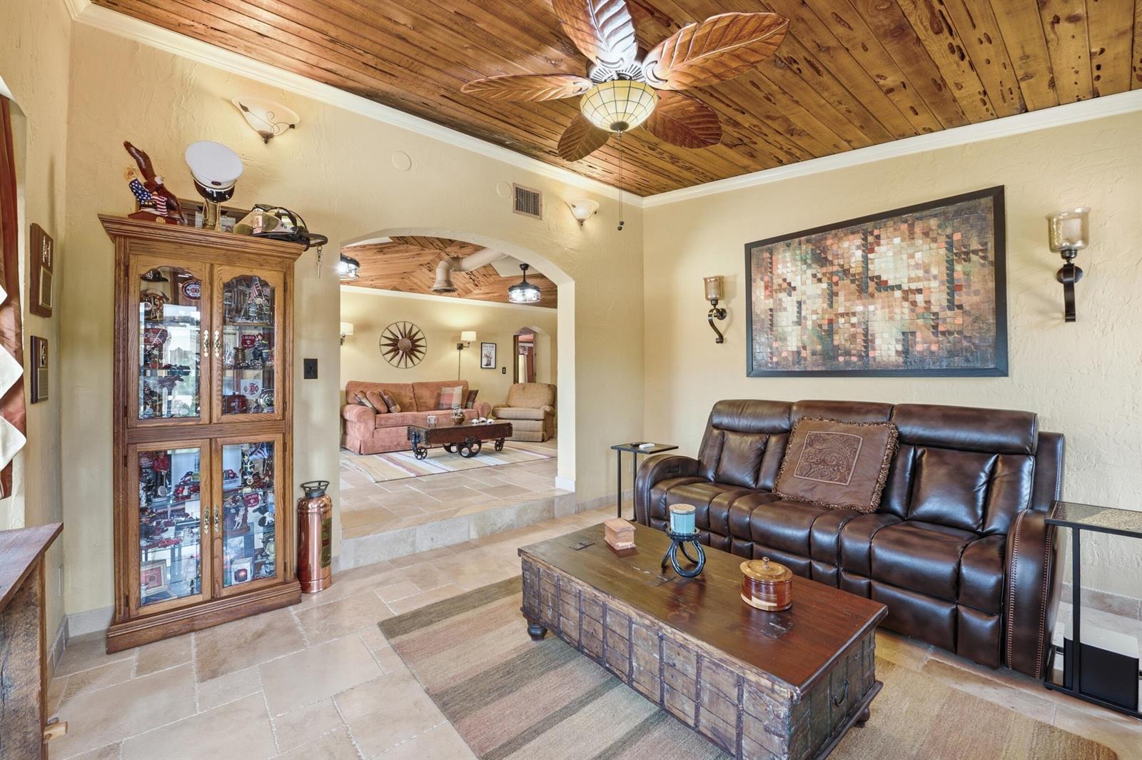 A living room features a wood-plank ceiling, tile floors, a leather sofa, and a display cabinet — 1055 S Brevard Avenue, Cocoa Beach FL 32931, COCOA BEACH, FL