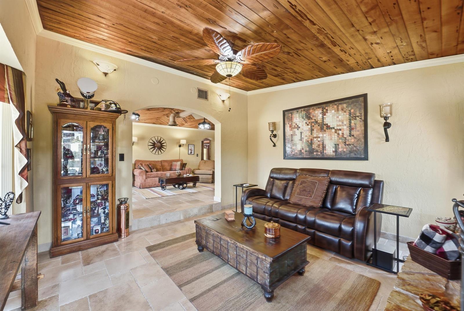 A living room features a wood-plank ceiling, tile flooring, a leather sofa, and an archway — 1055 S Brevard Avenue, Cocoa Beach FL 32931, COCOA BEACH, FL