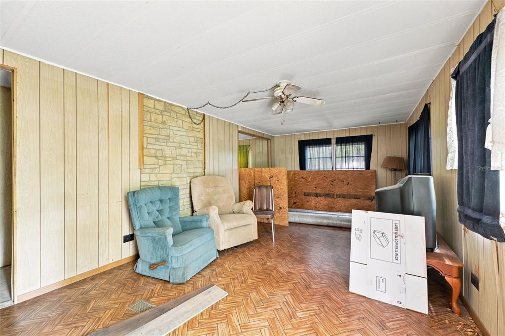 A living room features wood-paneled walls, a stone fireplace accent, and parquet flooring — 4734 S SLASH PINE AVENUE, HOMOSASSA, FL