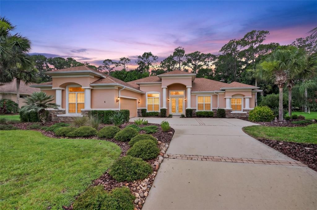 A single-story stucco house with a concrete driveway and landscaped yard at sunset — 6 SCARLET OAK CIRCLE, PALM COAST, FL