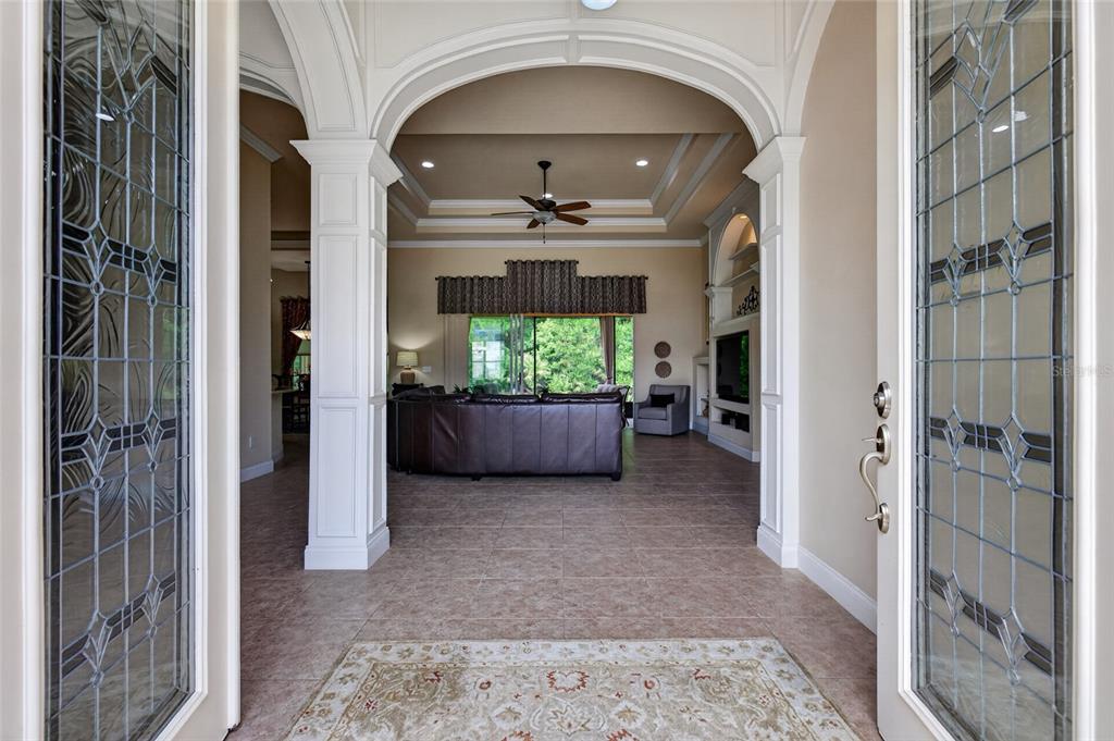 A view through a front doorway into a living room with tile floors and tray ceilings — 6 SCARLET OAK CIRCLE, PALM COAST, FL