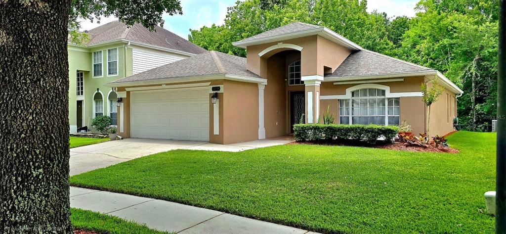 A tan single-story house with a two-car garage sits on a grassy suburban lot — 2930 RIVERS END ROAD, ORLANDO, FL