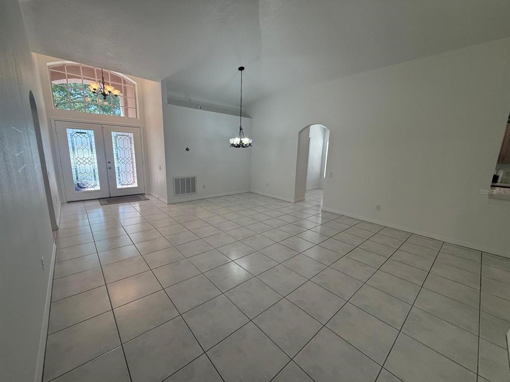 A bright, tiled dining area features a chandelier, high ceilings, and double front entry doors — 2930 RIVERS END ROAD, ORLANDO, FL