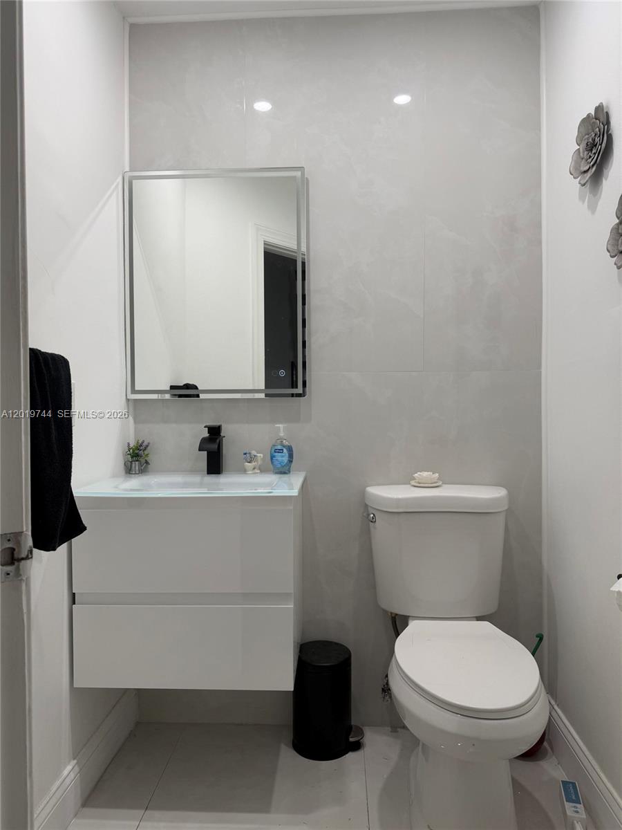 A small bathroom features a white vanity, a rectangular mirror, and a white toilet — 1481 NW 104th Ave, Plantation FL 33322, PLANTATION, FL