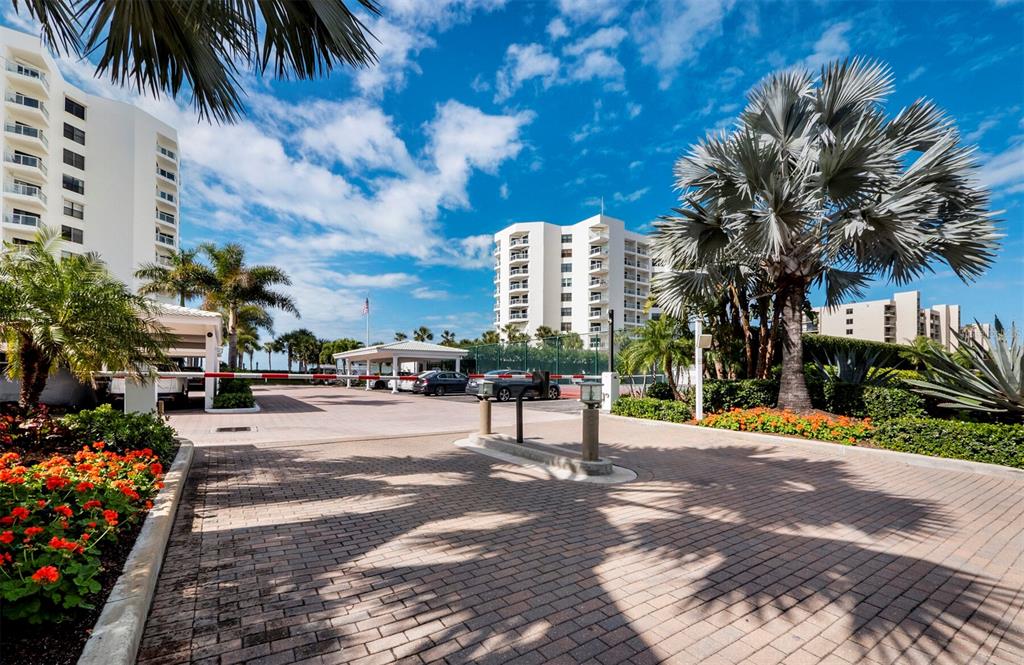 A paved driveway leads to a gated entrance with palm trees and multi-story residential buildings — 1050 LONGBOAT CLUB ROAD UNIT 903, LONGBOAT KEY, FL