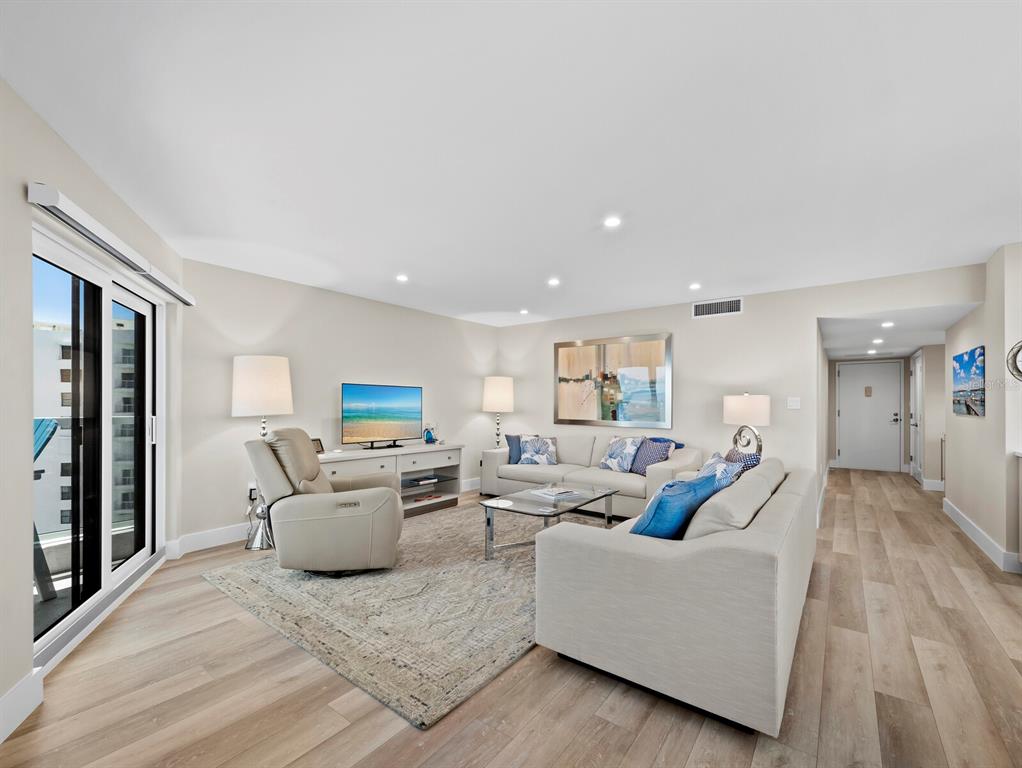 A living room features light wood flooring, a beige sofa, a recliner, and a television — 1050 LONGBOAT CLUB ROAD UNIT 903, LONGBOAT KEY, FL