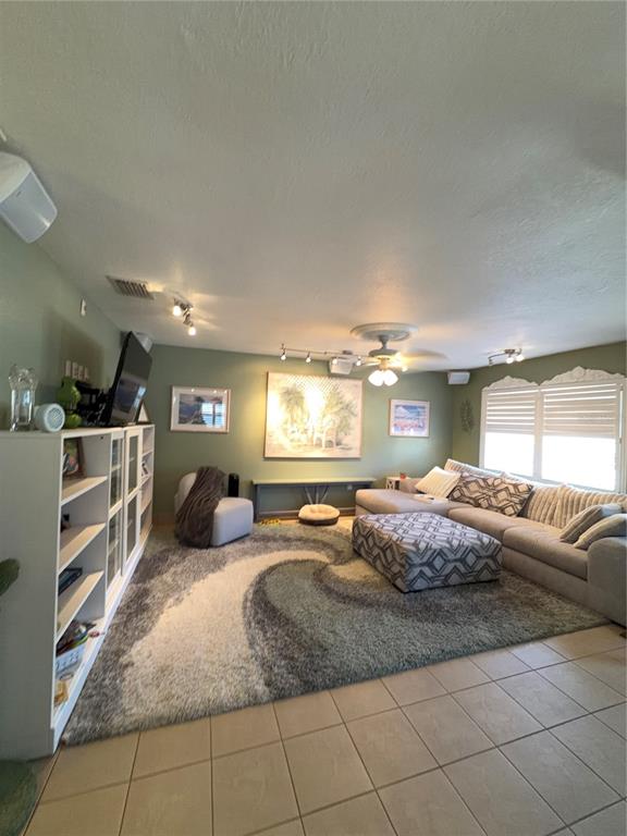 A living room features a large sectional sofa, patterned ottoman, area rug, and wall shelving — 11810 BOYNTON LANE UNIT 1, NEW PORT RICHEY, FL
