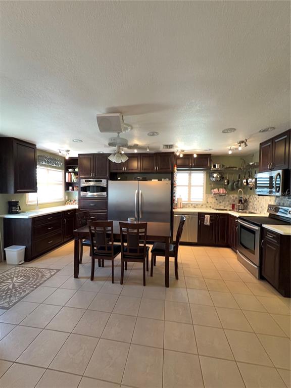 A kitchen features dark wood cabinets, stainless steel appliances, and a dining table with chairs — 11810 BOYNTON LANE UNIT 1, NEW PORT RICHEY, FL