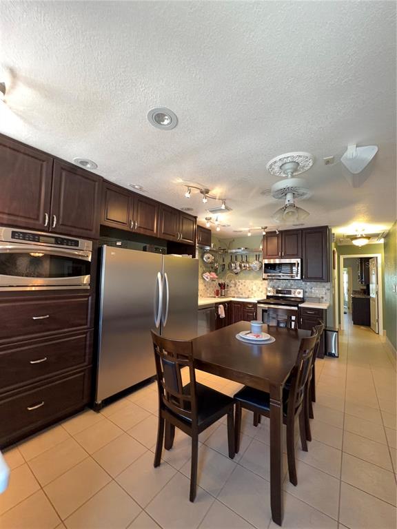A kitchen features dark wood cabinets, stainless steel appliances, and a dining table with chairs — 11810 BOYNTON LANE UNIT 1, NEW PORT RICHEY, FL