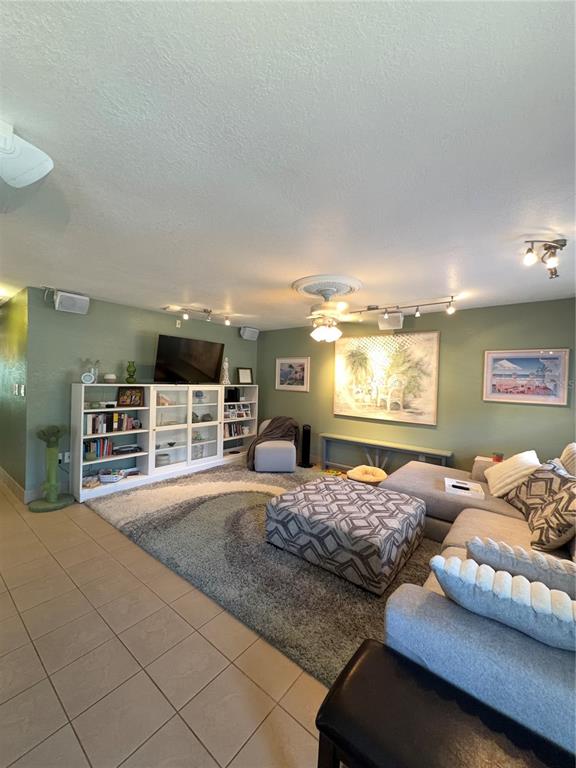 A living room features a large gray sectional sofa, a patterned ottoman, and built-in shelving — 11810 BOYNTON LANE UNIT 1, NEW PORT RICHEY, FL