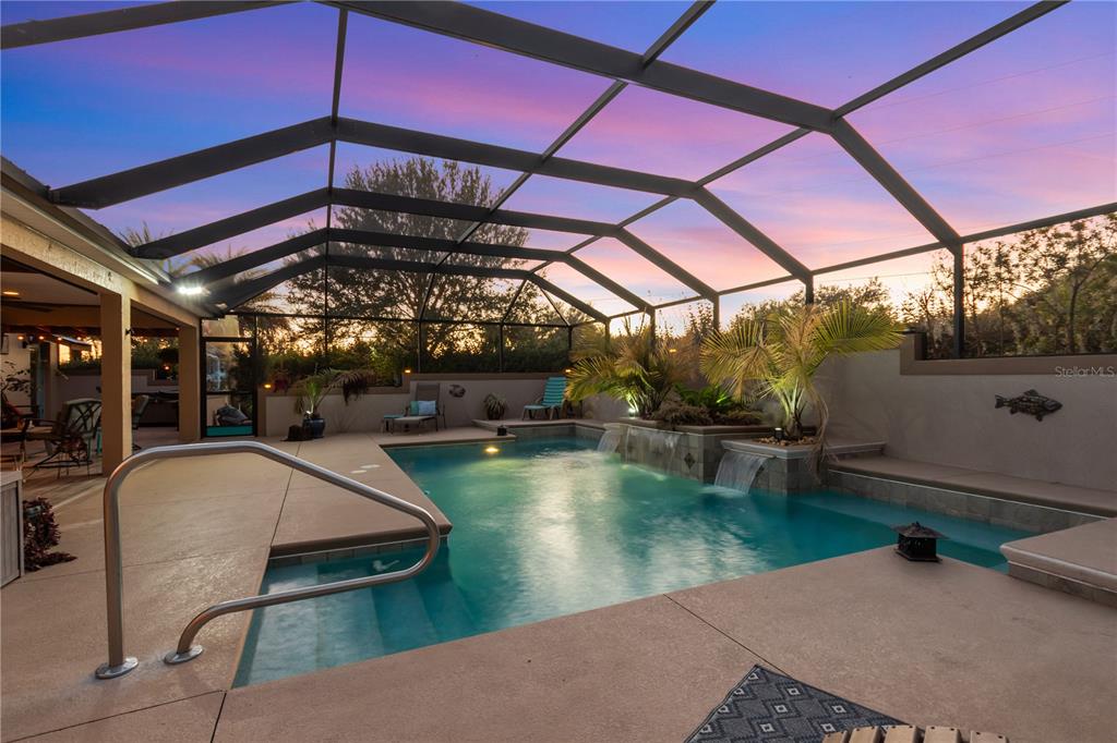 A screened-in patio features a swimming pool with water features and a concrete deck — 2611 JUPITER WAY, THE VILLAGES, FL