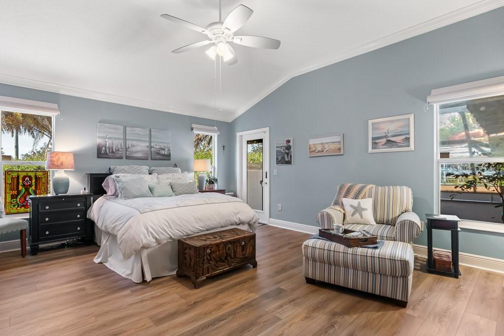 A bedroom with light blue walls, wood flooring, a ceiling fan, and a striped armchair — 2611 JUPITER WAY, THE VILLAGES, FL