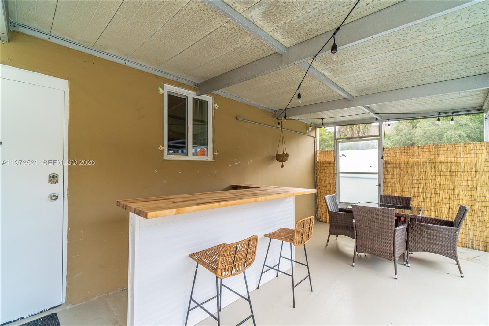 A covered patio features a white bar with a wood top, stools, and dining furniture — 13405 NW 6th Ave, North Miami FL 33168, NORTH MIAMI, FL