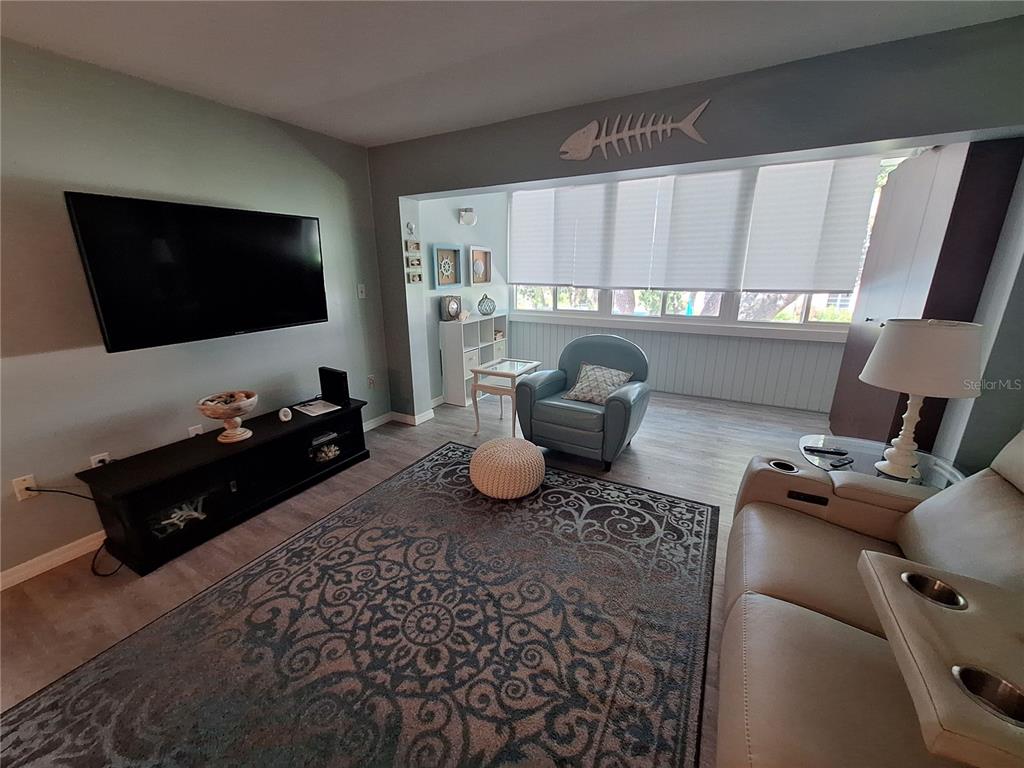 A living room features a wall-mounted television, a large patterned rug, and a seating area — 2437 HARBOR BOULEVARD UNIT 202, PORT CHARLOTTE, FL