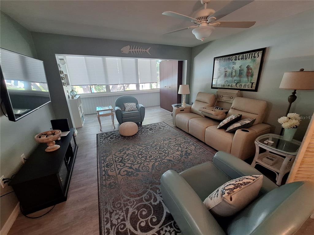 A living room features a tan reclining sofa, two blue armchairs, and a patterned rug — 2437 HARBOR BOULEVARD UNIT 202, PORT CHARLOTTE, FL