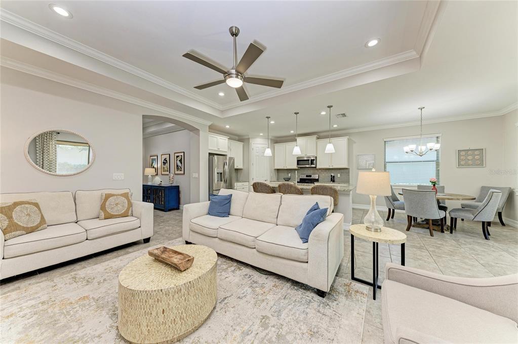 An open-concept living room and kitchen featuring neutral furniture, tile flooring, and a ceiling fan — 131 MARAVIYA BOULEVARD, NOKOMIS, FL