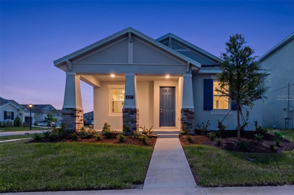 A single-story house exterior features a covered porch with stone-based columns and a blue door — 5237 WAYPOINTE BOULEVARD, APOPKA, FL