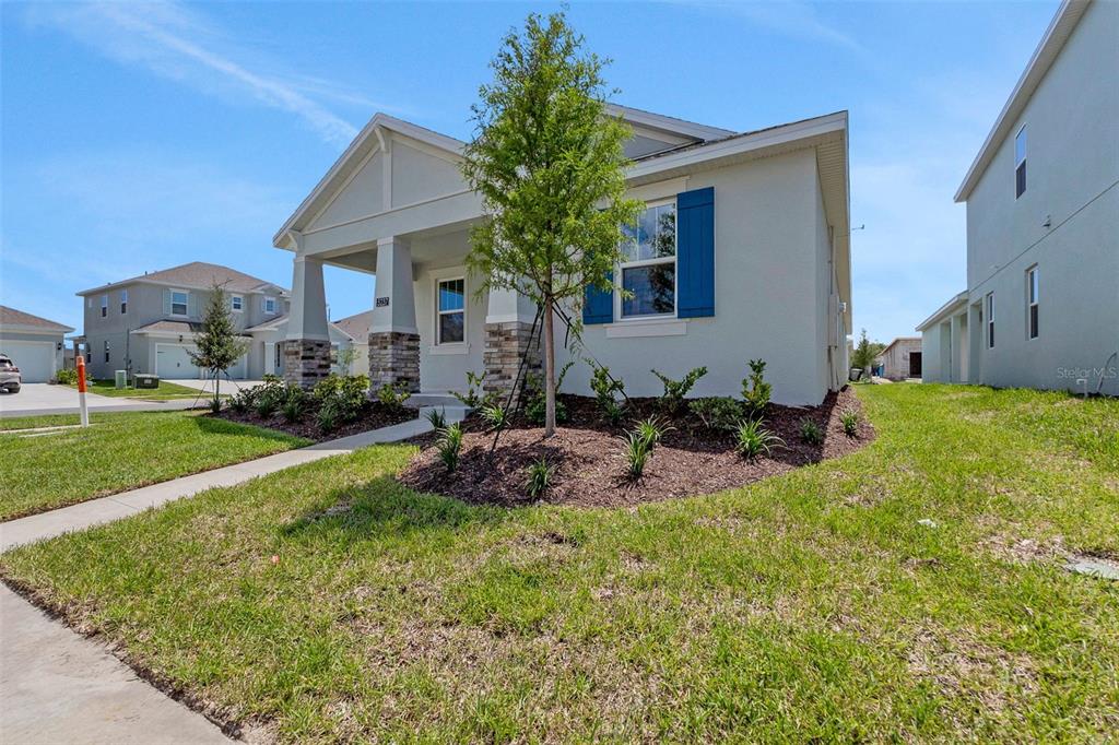 A single-story house with a covered porch, stone accents, and blue shutters on a lawn — 5237 WAYPOINTE BOULEVARD, APOPKA, FL