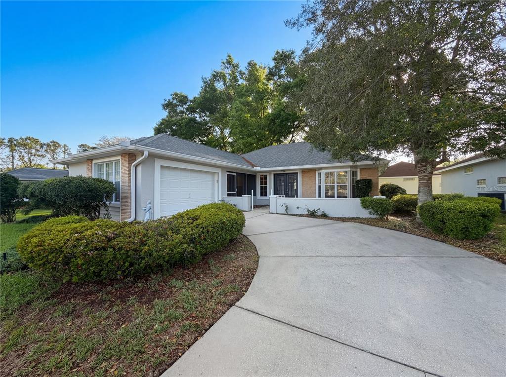 A single-story house with a white garage, a curved driveway, and mature landscaping — 7319 SW 115TH PLACE, OCALA, FL