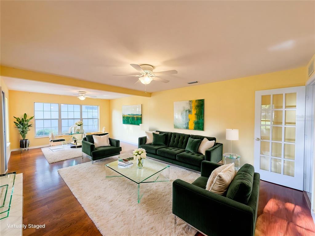 A living room with yellow walls, hardwood floors, a green sofa, and two green armchairs — 7319 SW 115TH PLACE, OCALA, FL