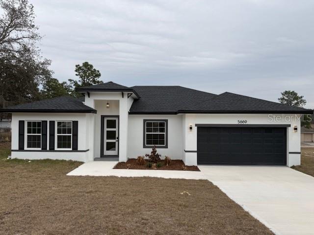 A single-story house with white stucco walls, a black roof, and a two-car garage — 5669 N CLAREMONT DRIVE, CITRUS SPRINGS, FL