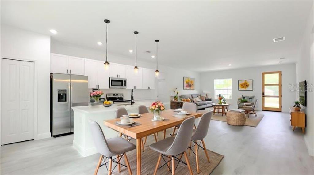 An open-concept kitchen and dining area features white cabinets, stainless appliances, and light flooring — 5669 N CLAREMONT DRIVE, CITRUS SPRINGS, FL