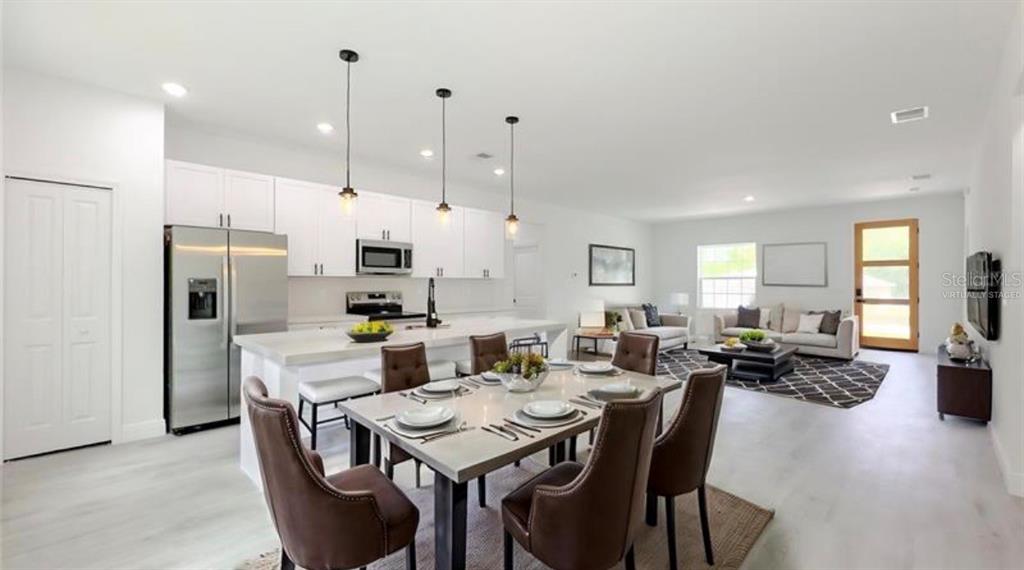 An open-concept kitchen and dining area features white cabinetry, a central island, and modern lighting — 5669 N CLAREMONT DRIVE, CITRUS SPRINGS, FL