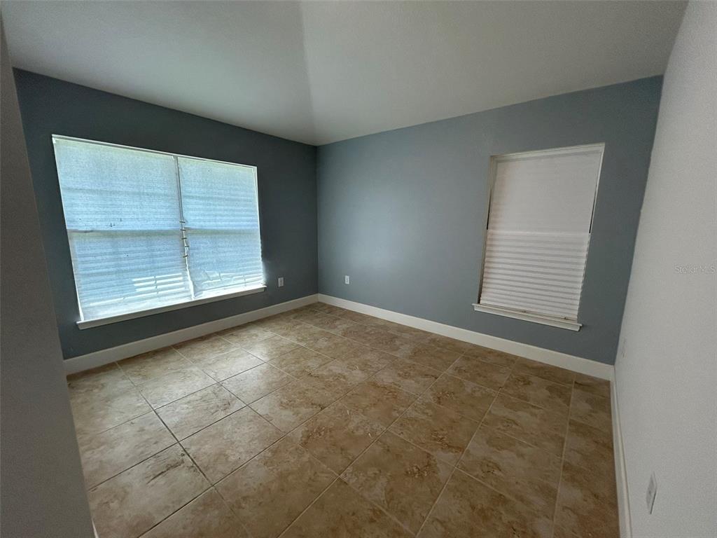 An empty room with blue walls, tile flooring, and two windows with white blinds — 1923 VILLIA STREET, LEHIGH ACRES, FL