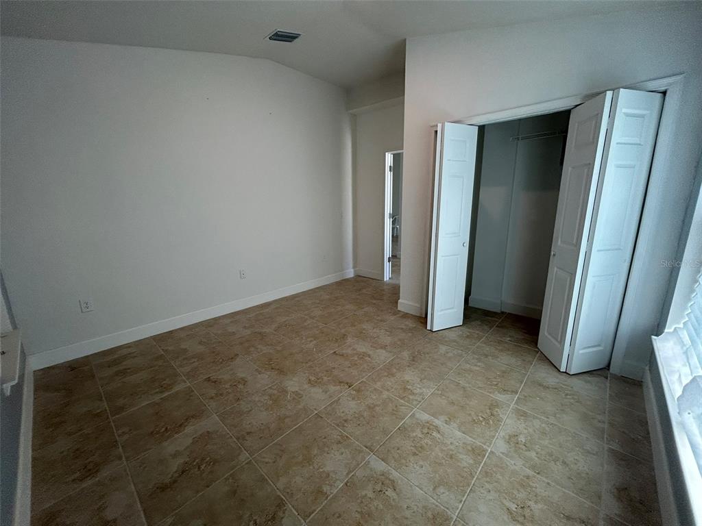 An empty room features tiled flooring, white walls, a closet with bi-fold doors, and a doorway — 1923 VILLIA STREET, LEHIGH ACRES, FL