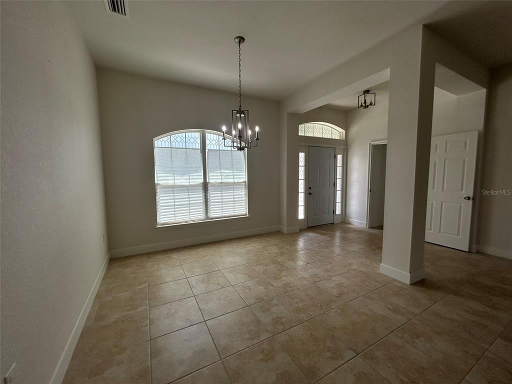 A dining room features tile flooring, a chandelier, and a front entryway with a door — 1923 VILLIA STREET, LEHIGH ACRES, FL