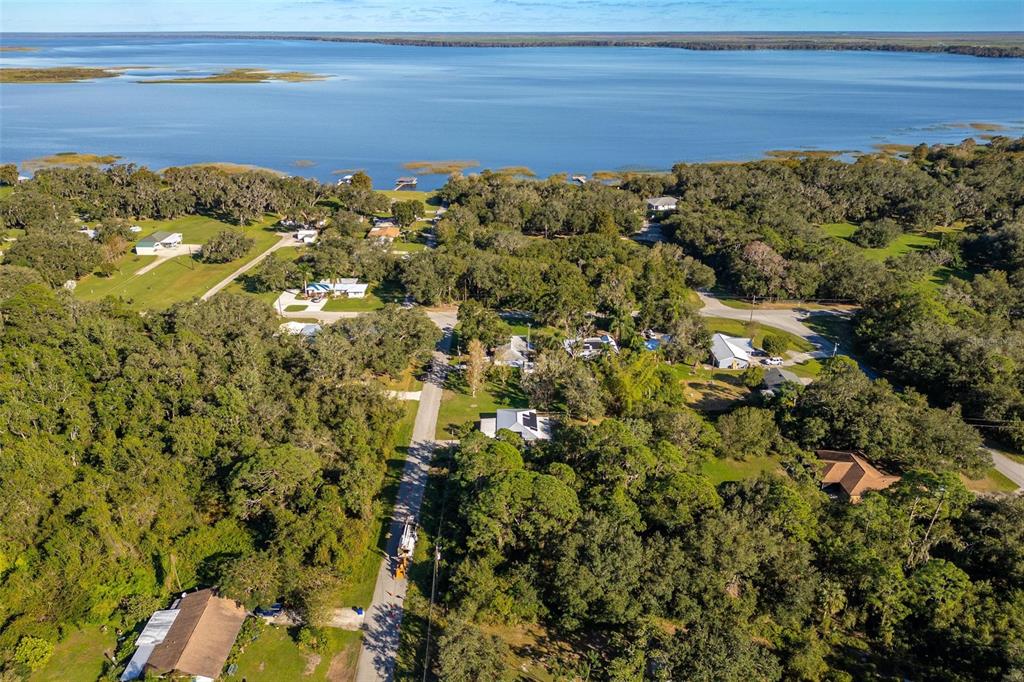 An aerial view shows houses nestled among dense trees near a large, calm lake — 1511 FRINGE STREET, LAKE PLACID, FL