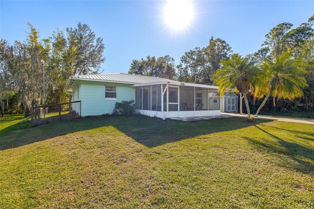 A light green house with a metal roof and a screened-in porch sits on grass — 1511 FRINGE STREET, LAKE PLACID, FL